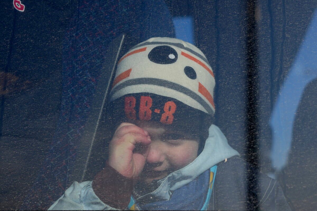 A child looks through a window of a bus carrying refugees fleeing the conflict from neighboring Ukraine in the border town of Przemysl, Poland, on Feb. 26, 2022. (Petr David Josek/AP Photo)
