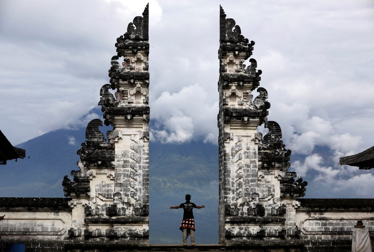 A Balinese man stands at the gate of Lempuyang temple looking toward Mount Agung volcano, in Karangasem Regency, Bali, Indonesia, on Dec. 2, 2017. (Reuters/Darren Whiteside)