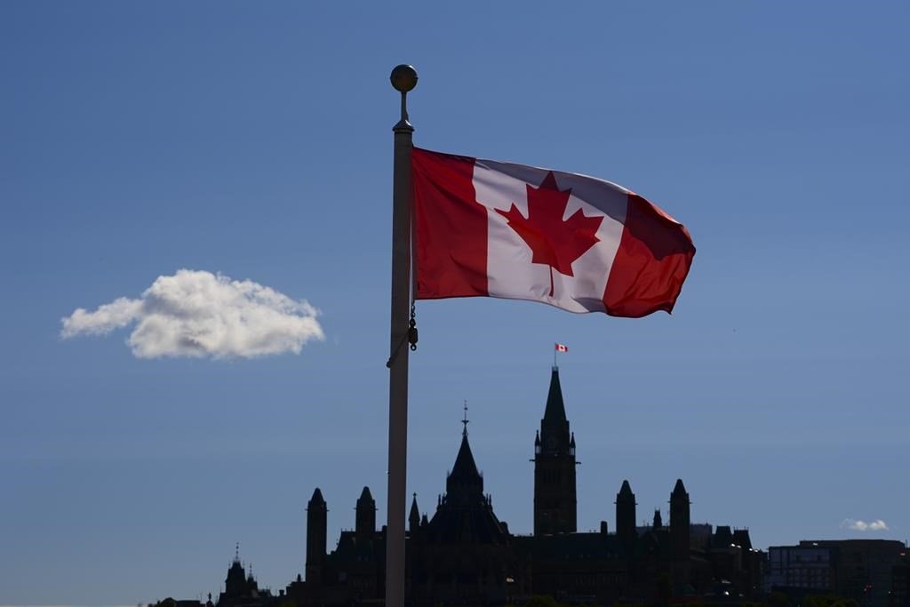 Canada's Parliament Hill is viewed below a Canada flag in Gatineau, Quebec, on Sept. 18, 2020. (Sean Kilpatrick/The Canadian Press)