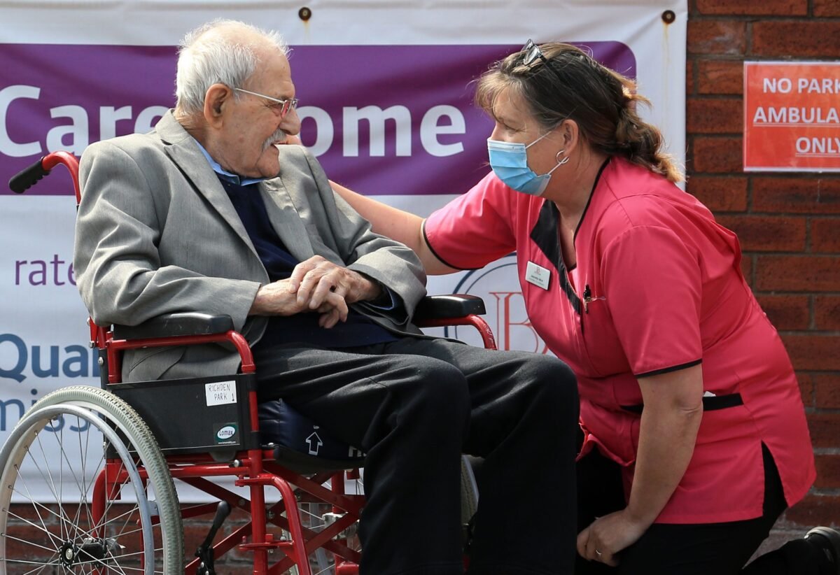 A care home resident talks with a carer outside a care home in Scunthorpe, northern England on May 4, 2020. (Lindsey Parnaby/AFP via Getty Images)