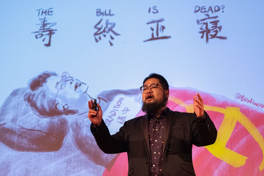 Chinese political cartoonist Badiucao speaks in front of one his satirical illustrations of Chief Executive of Hong Kong Carrie Lam with the title 'Is the Bill Dead' during the Be Water: Hong Kong v China event at Melbourne City conference centre on September 04, 2019 in Melbourne, Australia. (Asanka Ratnayake/Getty Images)
