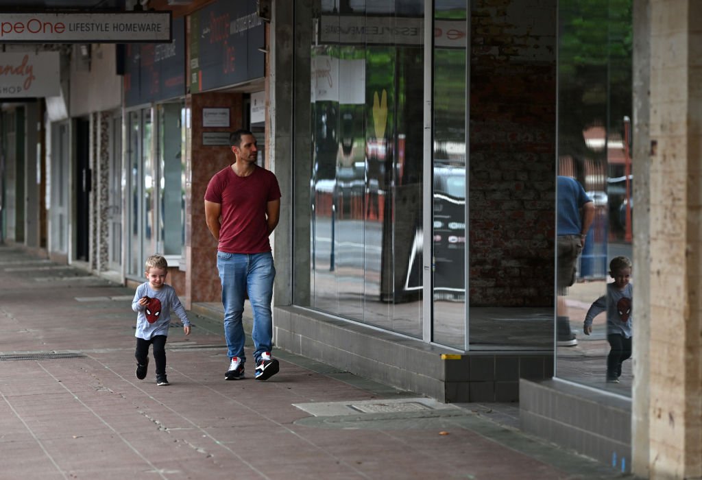 A father and his young son walk past shuttered businesses in the CBD of Lismore, New South Wales in Australia on May 15, 2022. (Dan Peled/Getty Images)