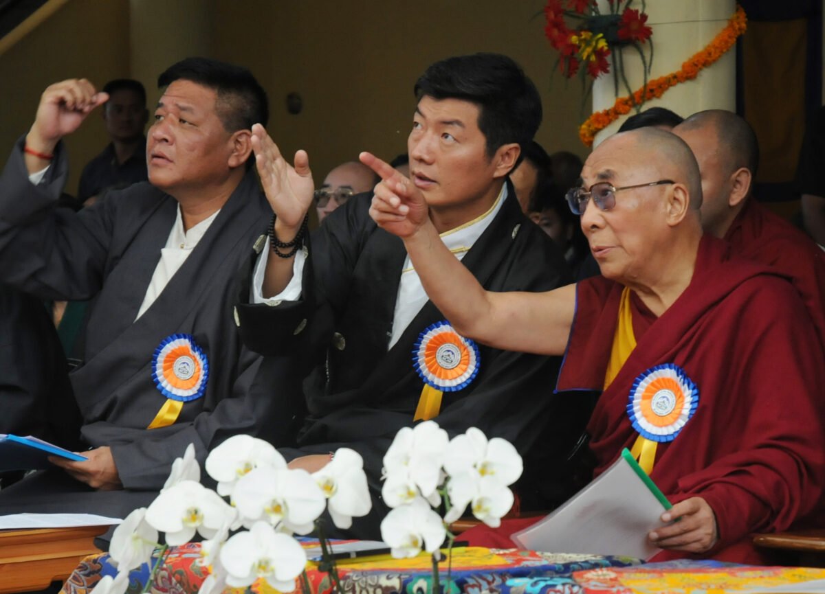 Tibetan spiritual leader the Dalai Lama (R), exile Tibetan Prime Minister Lobsang Sangay (C), and Speaker of the Tibetan Parliament-in-exile Penpa Tsering (L) gesture to a banner showing pictures of the Dalai Lama at different ages during his 77th birthday celebrations at the Tsuglakhang Temple in McLeod Ganj, Dharamsala, on July 6, 2012. The Tibetan leader, who fled his homeland for northern India in 1959 after a failed uprising against Chinese communist rule, announced in 2011 that he was giving up his political role to focus on spiritual duties. (STRDEL/AFP/GettyImages)