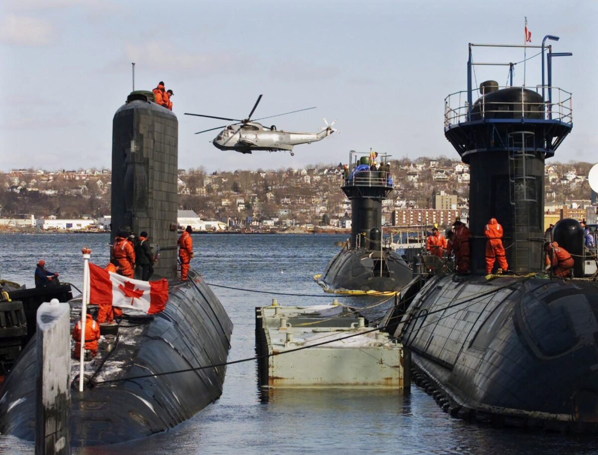 HMCS Corner Brook (L), the third of four Victoria-class submarines leased from Britain, arrives in Halifax as a Sea King helicopter flies past, in a file photo. HMCS Windsor (R) and HMCS Victoria sit at berth. (CP Photo/Andrew Vaughan)