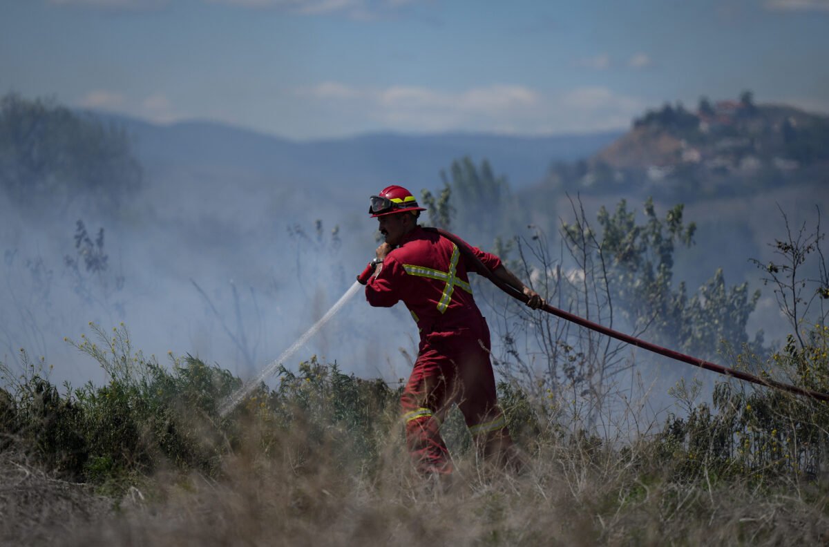 A firefighter directs water on a fire burning on an acreage behind a residential property in Kamloops, B.C., on June 5, 2023. (Darryl Dyck/The Canadian Press)