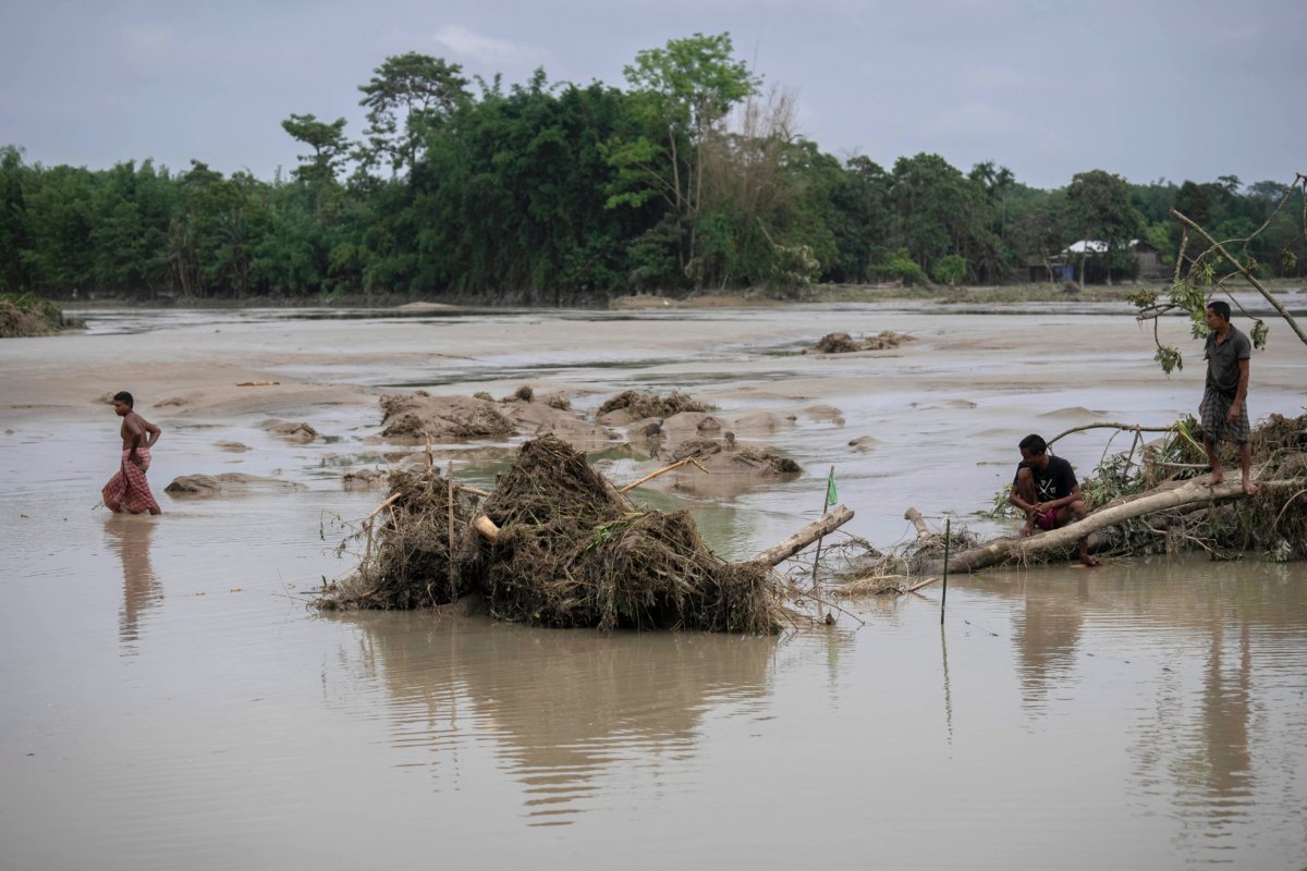 Villagers rest on an uprooted tree in flood waters in Barama, west of Guwahati, India, on June 23, 2023.(Anupam nath/AP Photo)