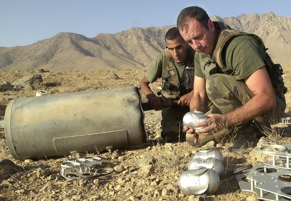 Soldiers with the French contingent of the International Security Assistance Force (ISAF) unload Russian made cluster bombs from a container found about 18 miles north of Kabul, Afghanistan, on Oct. 9, 2002. (AP Photo/Lynne Sladky)
