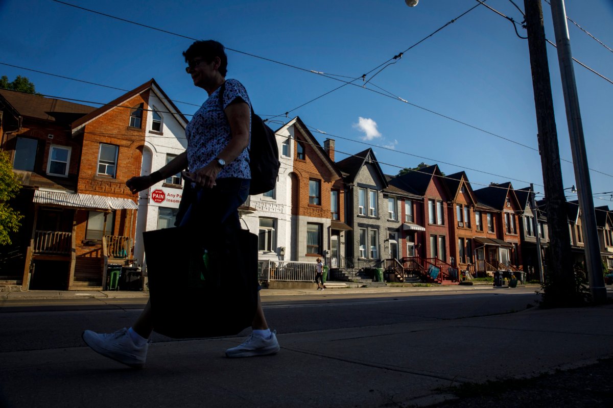 A person walks by a row of houses in Toronto on July 12, 2022. (The Canadian Press/Cole Burston)