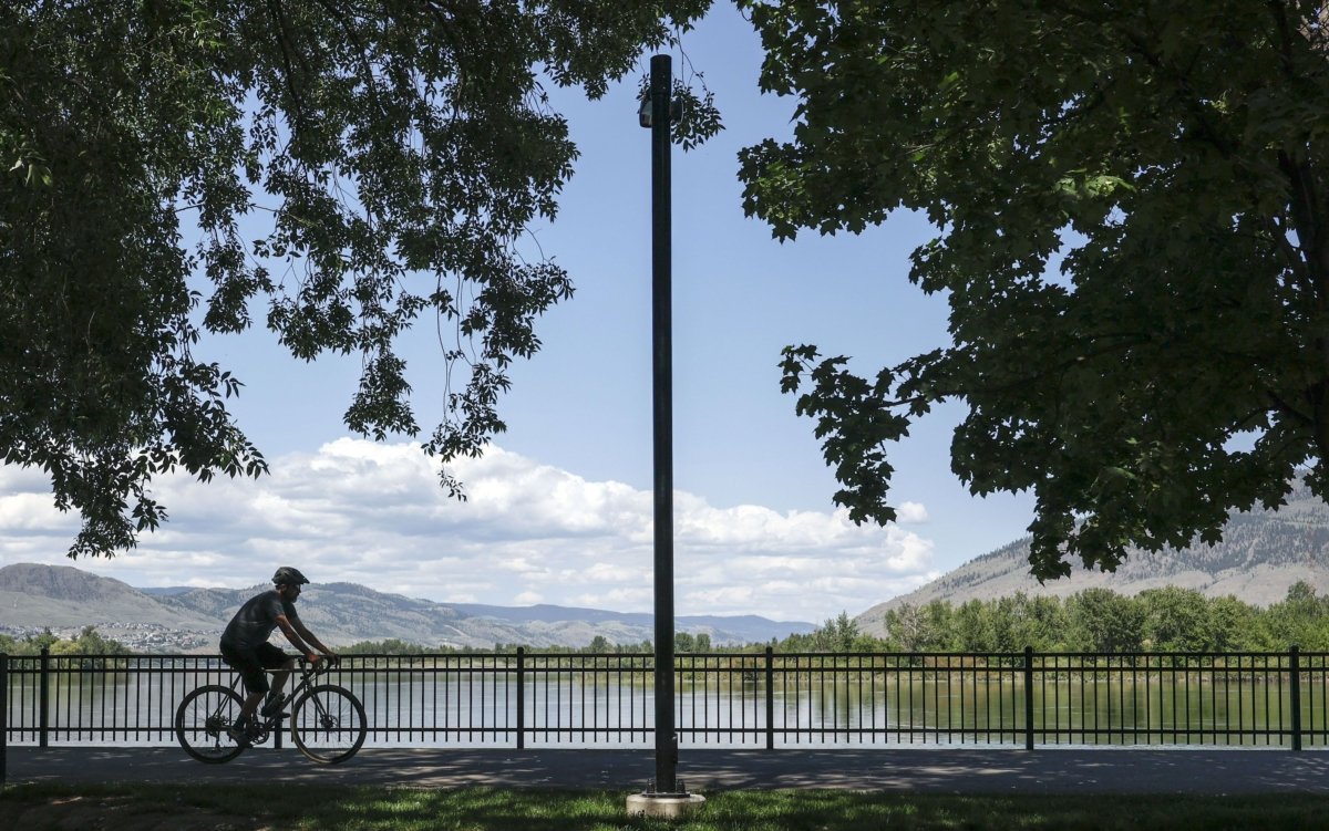 A cyclist rides past the Thompson River in Kamloops, B.C., on June 1, 2023. (The Canadian Press/Jeff McIntosh)
