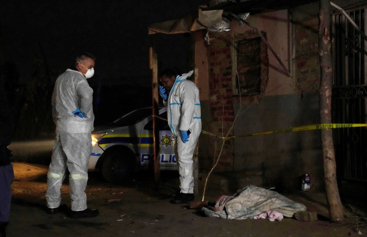 Police stand near a covered body in the Angelo settlement in Boksburg, South Africa, on July 6, 2023. (Themba Hadebe/AP Photo)