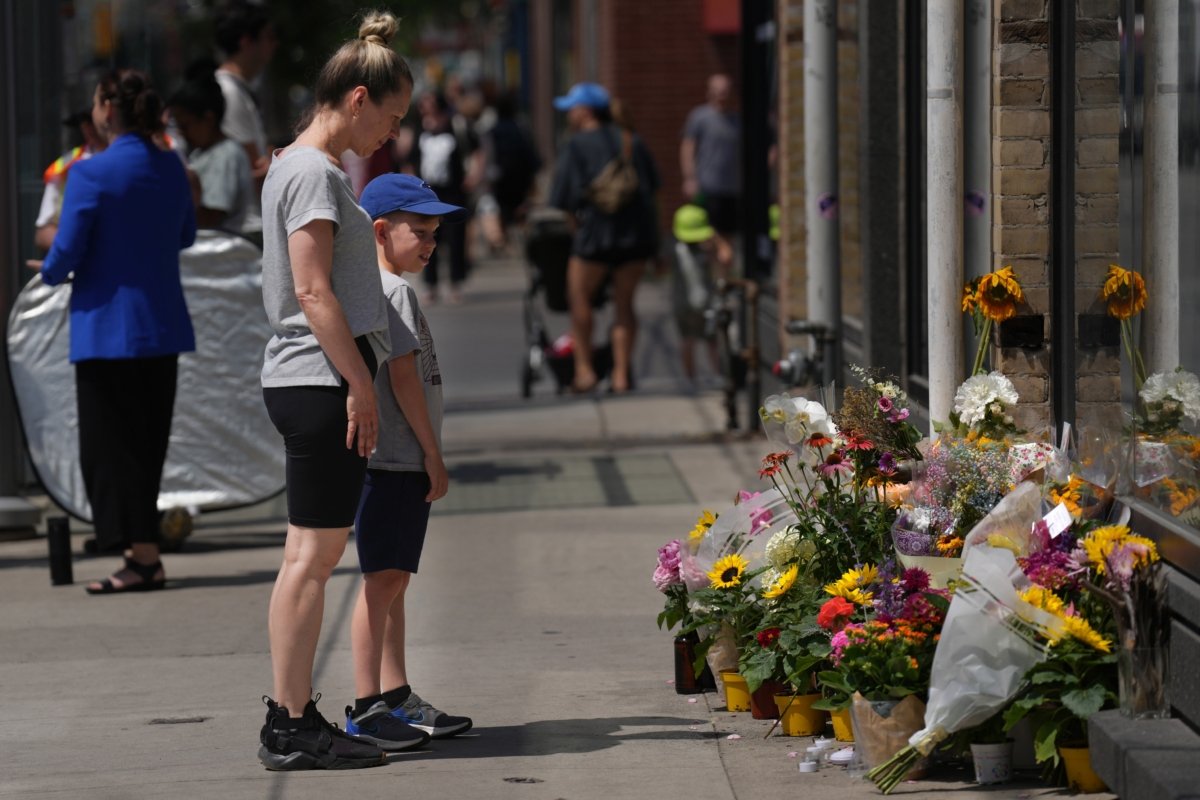 Passers-by stop to look at a makeshift memorial at the place where a mother of two, Karolina Huebner-Makurat, was killed by a stray bullet, in Toronto on July 10, 2023. (The Canadian Press/Chris Young)