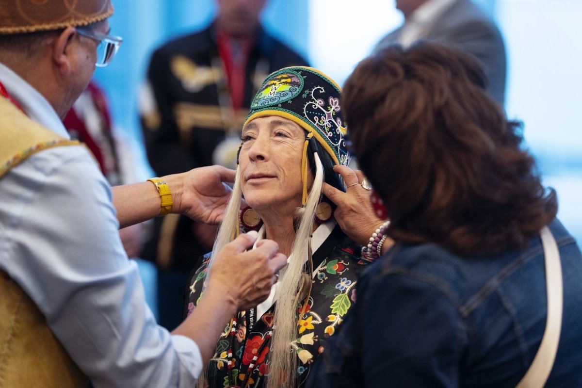 Newly-appointed Interim National Chief of the Assembly of First Nations Joanna Bernard (C) gets help adjusting her regalia before leading the grand procession during the AFN annual general assembly in Halifax on July 11, 2023. (The Canadian Press/Darren Calabrese)