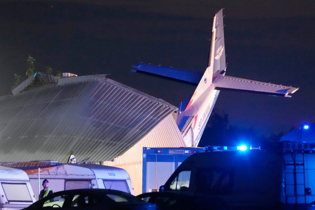 The tail of a Cessna 208 plane sticks out of a hangar after it crashed there in bad weather, killing several people and injuring others, at a sky-diving center in Chrcynno, central Poland, on July 17, 2023. (Czarek Sokolowski/AP Photo)