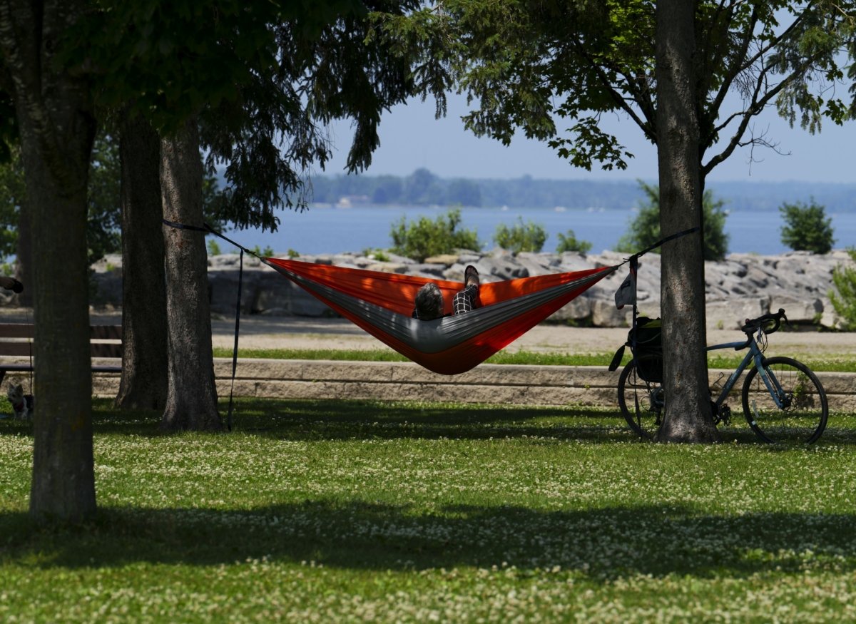 A person relaxes in the shade by the Ottawa River during a heatwave in Ontario, on July 4, 2023. (The Canadian Press/Sean Kilpatrick)